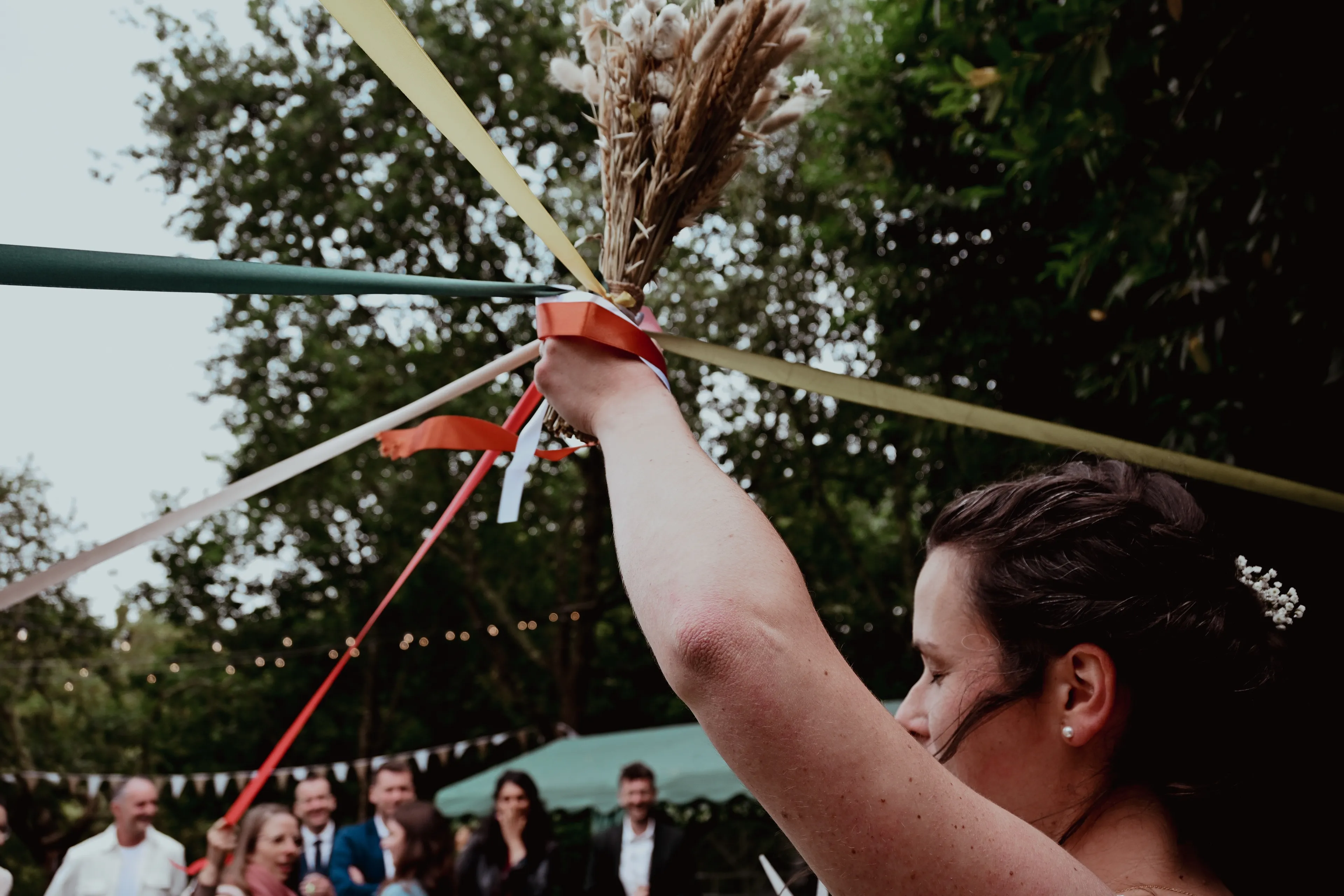 La mariée lève la gerbe de blé et les rubans du jeu de mariage, devant ses invités